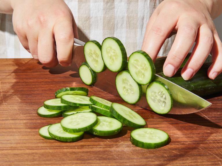 Peel red onion, halve, and thinly slice. Add to a bowl with the white wine vinegar and set aside to give it a quick pickle. Slice mini cucumbers and add to another bowl. Season with salt, toss, and set aside.