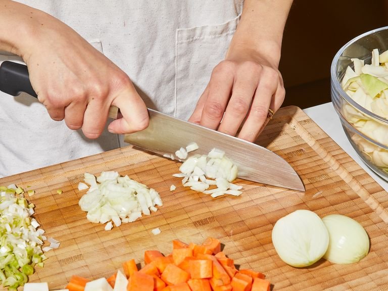 Remove the outer leaves and the core of the cabbage. Cut it into bite-size pieces. Peel the potatoes, celery, and carrots and cut into bite-size pieces. Clean the leek and finely dice together with the onions and garlic.