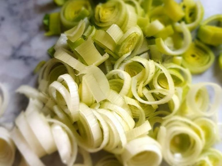Heat olive oil in a large pan and add crushed garlic. Finely chop the onion, leek, and spring onion whites and add to pan. Set aside the green ends of the spring onion. Sautee until onions are translucent.