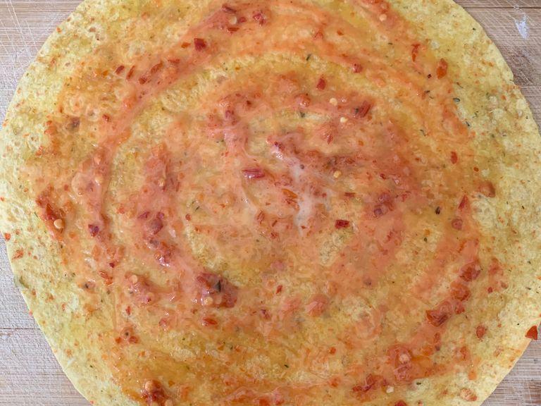 Add chilli sauce and coleslaw dressing on large-size tortilla and spread it evenly all over the base.