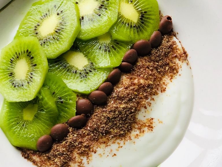 Put the yogurt in a bowl. Now peel the kiwi and cut it into slices. Distribute it on top of the yogurt on the side. Add the flax seeds. Place the chocolate chips and it's ready.