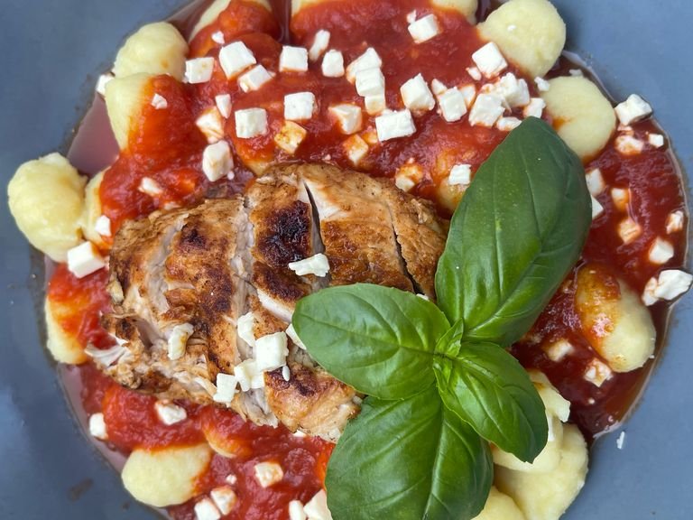 Die fertigen Gnocchi abgießen und auf einem Teller mit der Tomatensoße anrichten. Darauf ein Putenmedaillon legen und einige Fetawürfel darüberstreuen.