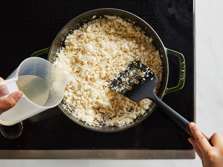 Sobald der Weißwein fast verdampft ist, den Blumenkohl-"Reis" hinzufügen. Mit Salz würzen, um einen Teil der Flüssigkeit austreten zu lassen, dann ca. 3 – 4 Min. unter ständigem Rühren kochen. Gemüsebrühe zugeben und die Hitze erhöhen, damit fast die gesamte Flüssigkeit köcheln und verdampfen kann.