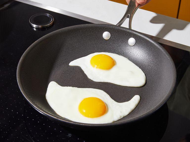 In the meantime, heat vegetable oil in another frying pan over medium heat. Crack in the eggs and season eggs with salt to taste. Continue frying until whites crisp on the edges and yolk is just set but runny in the center, or according to your preference.