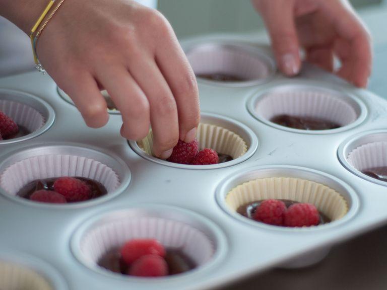Now, line muffin tin with muffin liners. Fill each one halfway full with batter. Place two raspberries in each cup and then top with remaining batter. Reserve leftover raspberries for serving. Place muffin tin in the freezer for approx. 10 min.