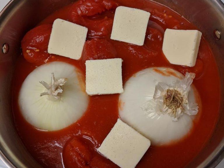 Empty tomatoes into sauce pan, cut onion in half and place cut side down into pan, slice up the butter and place it around the sauce, sprinkle a pinch of salt over everything. Bring to a simmer over medium-high heat.