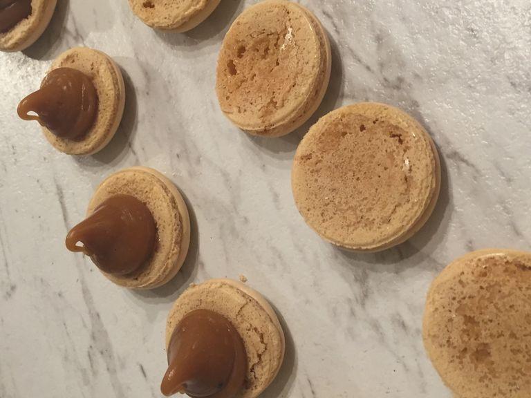 Fill butter caramel into a piping bag with a wide, round decorating tip. Squeeze a dollop of caramel onto a macaron, then gently press another macaron half on top. Cool or enjoy immediately.