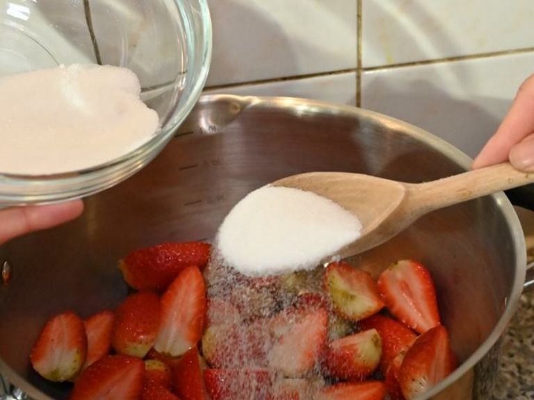 Erdbeeren und Zucker in einen Topf geben und bei geringer Hitze köcheln lassen, um das Erdbeercoulis zuzubereiten.
