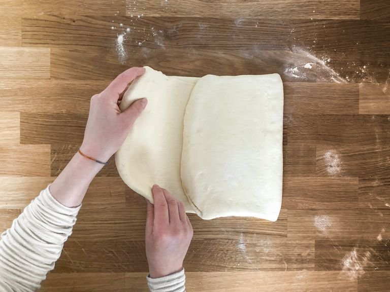 Now roll out the dough, one last time, and use a pizza roller to cut triangles to finally form the croissants. In the short side of the triangle, make a 0.5-in. (1-cm) long cut in the middle. Pull the two corners of the short side slightly apart and then roll up the dough towards the top. Repeat for remaining pieces. Place the croissants in an airtight container, making sure that there is enough space between each. Close with the lid and leave to rest overnight in the fridge.