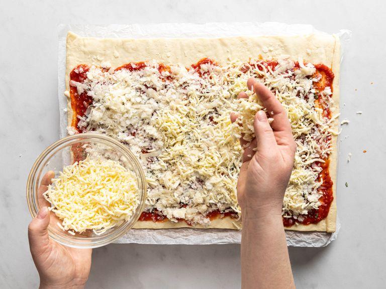 Preheat the oven to 220°C/430°F. Roll out pizza dough and spread approx. one-third of the sauce over the dough. Sprinkle chili flakes, rosemary, and thyme on top, then add Parmesan and mozzarella cheese. Roll up the dough and slice into even rolls.