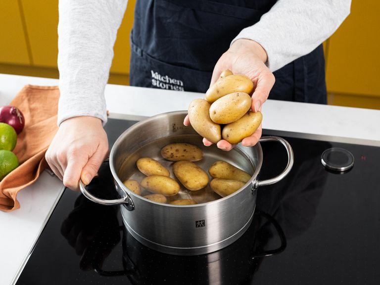 Den Ofen auf 200°C vorheizen. Einen Topf mit Salzwasser aufstellen und die Kartoffeln gar kochen, bis du sie leicht mit einer Gabel einstechen kannst. In einem Sieb abtropfen lassen, danach mit einem Küchentuch trocknen.