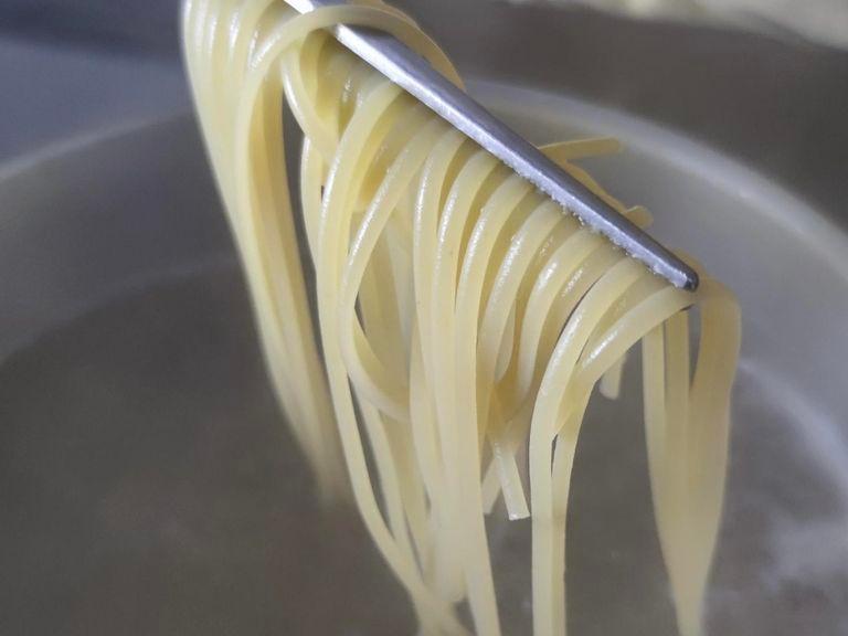 Knoblauch und die Schalotte in feine Würfel schneiden. Danach den Schnittlauch in feine Ringe schneiden. Den Parmesan reiben. Die Spaghetti gemäß Packungsanweisung in Salzwasser kochen. Beim Abgießen etwas Kochwasser auffangen.