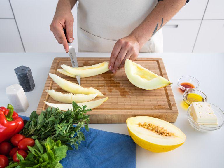 Remove peel and seeds of the honeydew melon, then slice into pieces. Slice red onion and quarter the tomatoes. Halve cucumber two times lengthwise, then cut into bite-sized pieces. Remove seeds from bell pepper, then dice. Add all ingredients to a bowl and season with salt. Slice feta cheese into cubes and set aside until serving.
