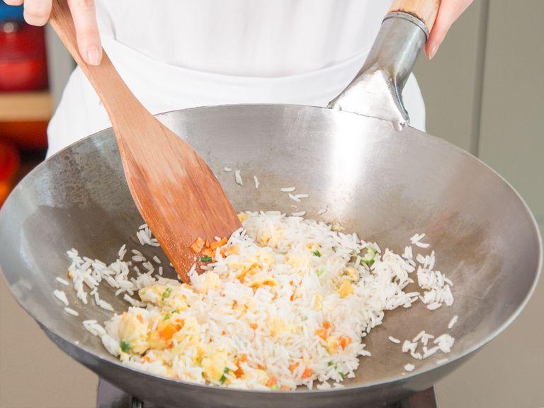 Gekochten Reis und Karottenwürfel dazugeben. Mit Salz und Pfeffer würzen. Kochwein dazugeben und auf höchster Stufe anbraten.