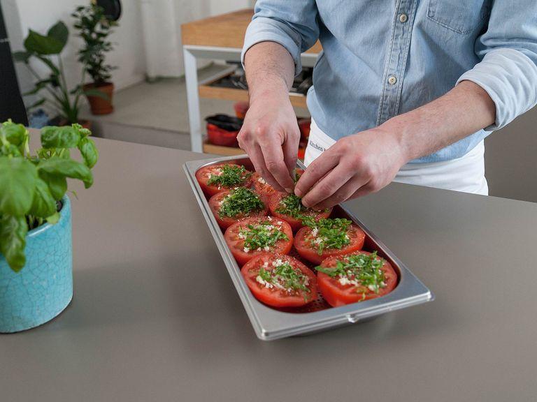 Place halved tomatoes in cooking container with cut side facing up. Top with chopped garlic, season with salt and pepper, and spread basil and feta cheese on top.