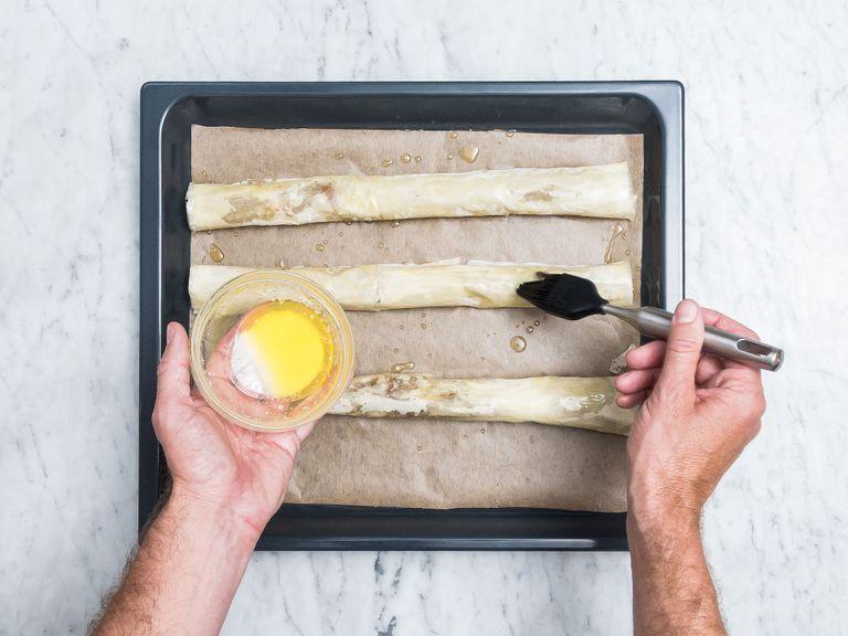 Roll up the phyllo dough tightly, starting with the filling-side. Transfer to a parchment-lined baking sheet and repeat the process twice more. Brush remaining butter on the phyllo dough rolls and bake baklava at 180°C/350°F for approx. 15 – 20 min. until golden brown.