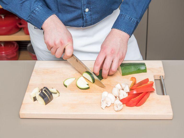 Paprika entkernen und in dünne Streifen schneiden. Zucchini längs halbieren, Aubergine vierteln und Champignons halbieren. Zucchini, Aubergine und Champignons klein schneiden und in eine Schüssel füllen.