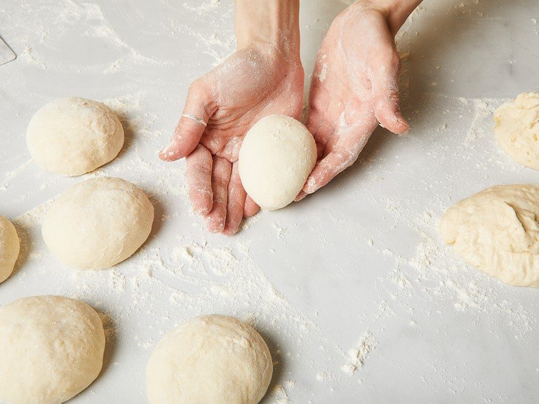 When doubled, transfer dough to a lightly floured work surface and gently knead to release air from the dough. Shape into a loose ball with only as much flour as needed, then divide into equal-sized (or equal-weight, if you want to be precise with a scale) pieces, making around 6-8 buns, depending on how big you want your burger buns. After rising, the dough will weigh about 1 kg. That would then be about 125 g per dough ball for 8 buns or 166 g for 6 buns. Then shape each into firm balls and place on a baking sheet lined with parchment paper. Cover with a kitchen towel and let rise for another approx. 30 min. until they look plumper.