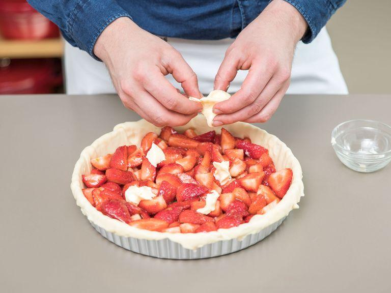 Das erste Stück Teig ausrollen. Den Teig in die Form legen, sodass ein 1 – 2 cm hoher Rand übersteht. Die Erdbeermischung einfüllen. Die restliche Butter kleinschneiden und auf den Erdbeeren verstreuen.