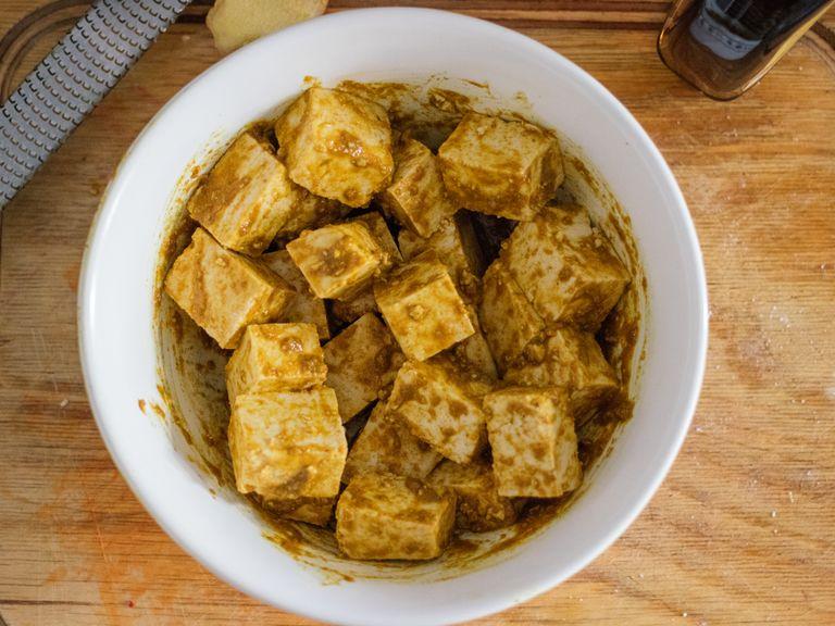 Tofu in ca. 2 cm breite Würfel schneiden. Geröstetes Sesamöl, Sojasauce, Ahornsirup, gemahlenen Kreuzkümmel, Koriander und Kurkumapulver in eine Schüssel geben. Ingwer und Knoblauch direkt in die Schüssel reiben und alles verrühren. Die Tofuwürfel in die Schüssel geben, alles gut vermengen, bis sie von der Soße ummantelt sind. Ca. 30 Min. ziehen lassen (je länger, desto besser).