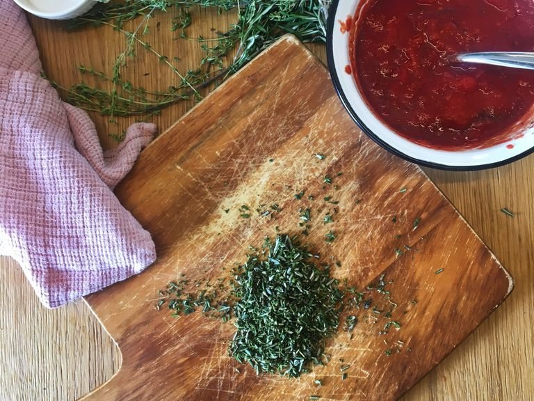 Roughly chop rosemary and thyme. Use a fork to press and break down the canned tomatoes. Season with salt and pepper.