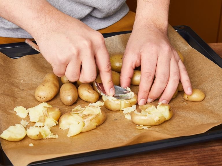 Den Ofen auf 220°C vorheizen. Die Kartoffeln in einen großen Topf mit gesalzenem Wasser geben. Zum Kochen bringen und ca. 10 Min. kochen, bis sie gar sind. Die Kartoffeln abgießen und auf ein Backblech geben. Um die Kartoffeln zu "smashen", mit einem Löffel oder dem Boden einer Pfanne die Kartoffeln leicht nach unten pressen, um sie zu zerdrücken.