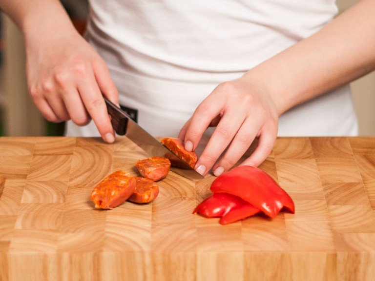 Paprika in vier gleich große Stücke und Chorizo in dicke Scheiben schneiden.