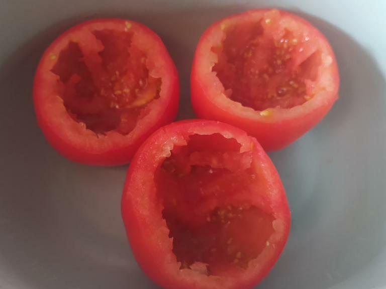 Zwiebeln klein schneiden und die Tomaten putzen und einen Deckel abschneiden, die Tomate anschließend aushöhlen und den Inhalt zur Seite geben (Wir brauchen ihn noch!). Die Tomaten in eine ofenfeste Form geben.