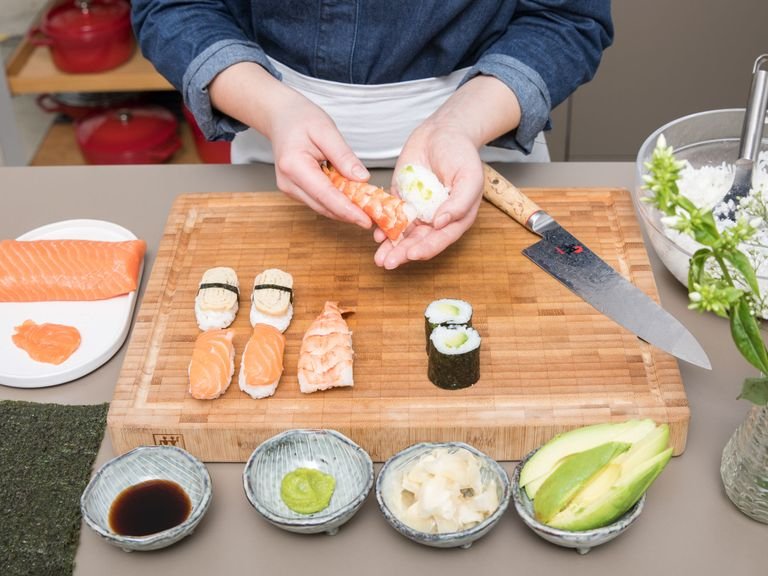 Für die Nigiri das Lachsfilet in Scheiben schneiden. Gekochten Sushireis mit den Händen in eine ovale Form bringen und Wasabi nach Geschmack darauf streichen. Mit einer Scheibe vom Lachsfilet belegen. Mit restlichen Zutaten wiederholen und weitere Avocado Maki und Nigiri zubereiten. Sushi mit Wasabi, Sushi-Ingwer und Sojasauce als Dip servieren. Guten Appetit!