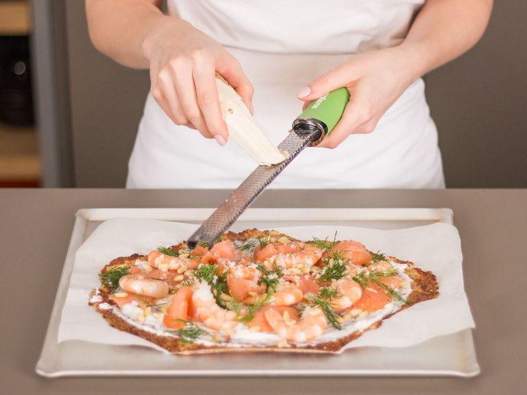 Ricotta gleichmäßig über die Blumenkohl-Pizza geben. Anschließend mit Lachs, Shrimps, Pinienkernen und frisch geriebenem Meerrettich belegen. Mit frischem Dill garnieren und servieren. Guten Appetit!