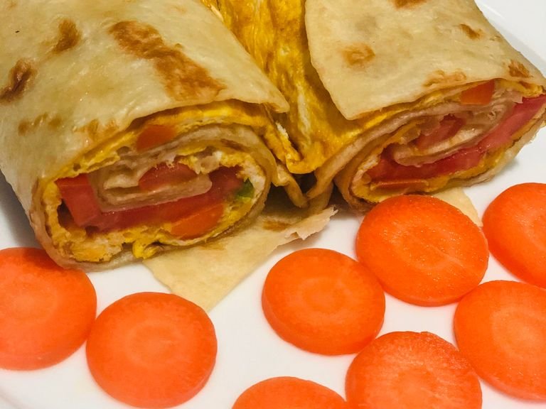 Get 300g of flour, add 1/6 tbsp of salt, add olive oil and mix. Keep the dough for 30 minutes and then fly a chapati, Get 2 raw eggs, add chopped onions add 1/8 tbsp of salt and mix, then fly the eggs. Put the fried eggs on top of the chapati, add 4 slices of fresh tomatoes, add 4 slices green peppers and then roll it together. After cut into pieces and serve with carrot slices aside