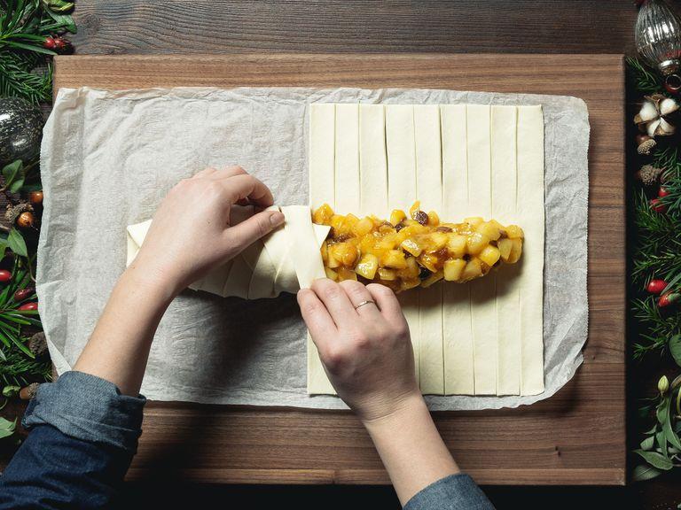 Place the puff pastry on a cutting board and, using a bench scraper, cut strips into the dough approx. 2 cm/3/4-in. wide and 8 cm/3-in. long. Add the pear filling to the middle and, starting at either end and working to the middle, fold the strips over the filling, alternating top and bottom strips for a braided effect. Combine the egg yolk with the heavy cream and brush onto the strudel.