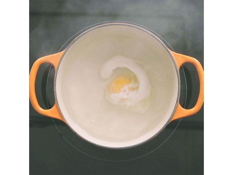 In einem mittelgroßen Topf etwas Wasser zum Kochen bringen. Salz und Weißweinessig hinzugeben. Mit Hilfe eines Kochlöffels einen Strudel im Wasser erzeugen. Langsam das Ei in das Zentrum des Strudels geben. Ca. 3 Min. kochen, bis das Eiweiß fest ist.