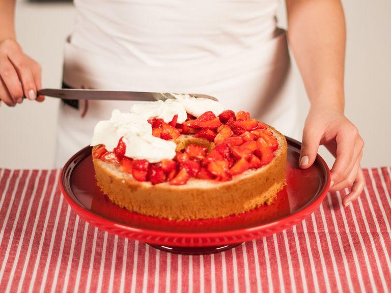 Den Kuchenboden auf einer Servierplatte anrichten. Mit der Hälfte der Erdbeeren belegen und mit Zitronensaft beträufeln. Die Sahne auf den Beeren verteilen und den nächsten Kuchenboden darauf platzieren.
