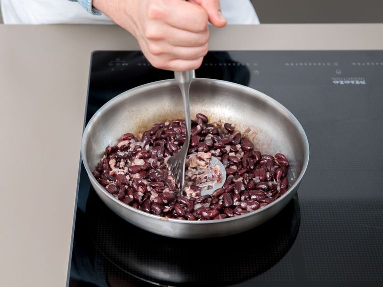 Next, we will make the beans. Cut the onion. Drain and rinse the beans, heat some oil in a pan, fry the onion, then add the beans and mash them in the pan, or leave them whole because they will still taste great.