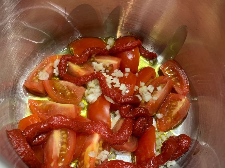 Um die Tomatensauce zuzubereiten, stellt man zunächst einen Topf bei geringer Hitze auf den Herd und fügt Olivenöl hinzu. Die frischen Tomaten vierteln, den Knoblauch klein hacken und mit den Tomaten und Tomatenmark in den Topf geben und die Hitze etwas erhöhen. Gelegentlich umrühren und nach ca. 3 Minuten den Inhalt der Dosen mit stückigen Tomaten hinzugeben. Mit italienischen Kräutern, Salz und Pfeffer würzen und gelegentlich umrühren.