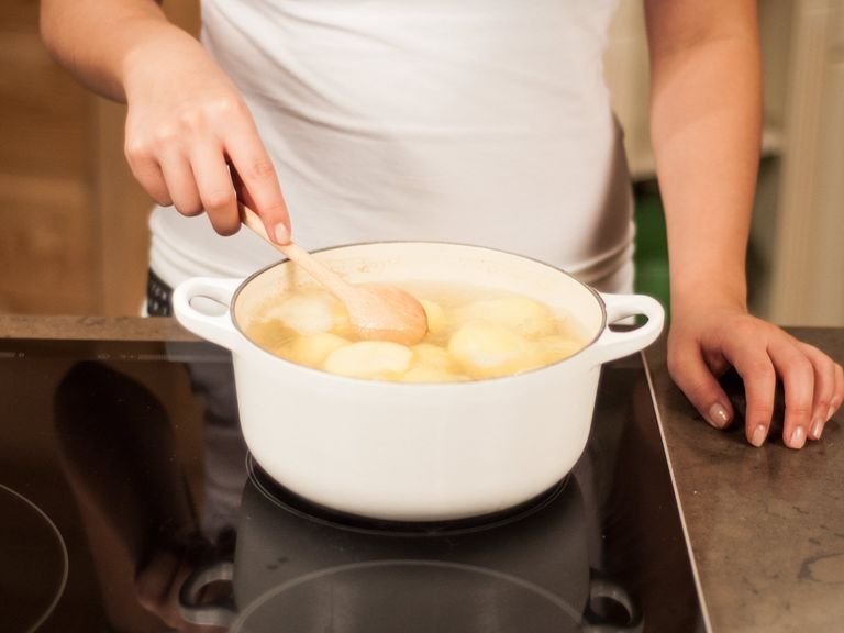 Kartoffeln in einen großen Topf geben. Mit Wasser bedecken, salzen und aufkochen. Anschließend die Hitze reduzieren und für ca. 20 – 30 Min. gar köcheln lassen. Abgießen und ca. 15 Min. zum Abkühlen beiseitestellen.