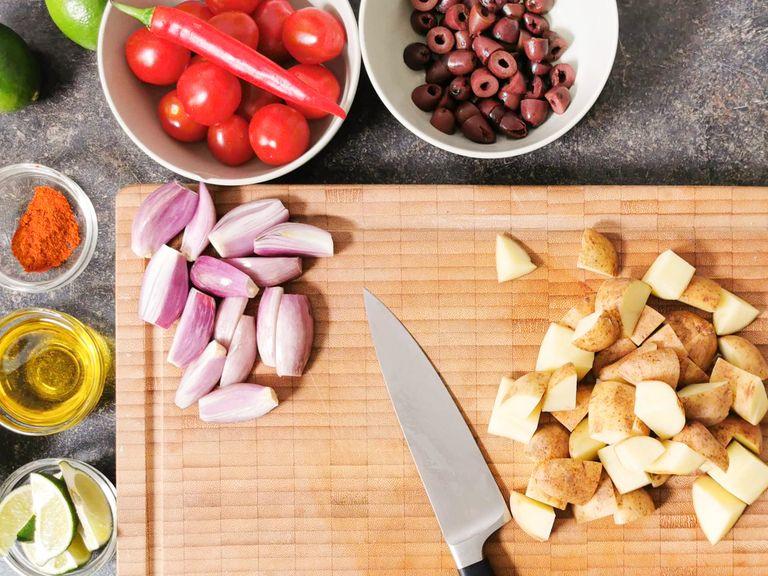 Preheat the oven to 200°C/390°F. Cut the lime into wedges. Roughly chop the hazelnuts. Cube the potatoes. Peel and halve the shallots. Halve the chili. Drain olives and slice them in half. Trim asparagus ends, then peel.