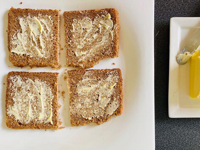 Take 4 slices of rye bread. Spread some butter on one side of the slices and place in the oven to heat them. Remove from the oven as soon as the butter has melted.