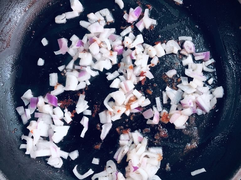 In the same pan, sauté the onion on medium heat until transparent, adding more oil if necessary. Next, add the chopped garlic and continue sautéing until the garlic releases fragrance.