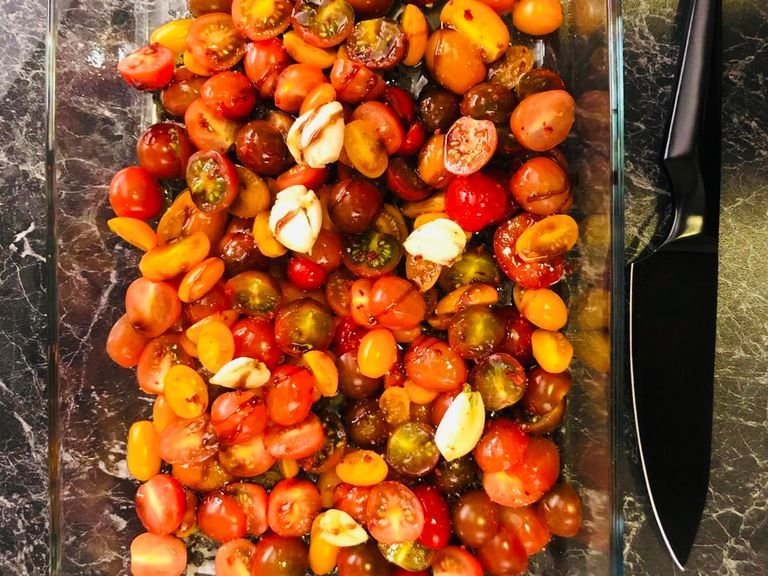 Preheat the oven to 180 degrees C fan. Cut the tomatoes in half, peel the garlic and crush them with the side of the knife. Then place them all together in the oven dish. Spoon 1/2 (50 ml) of the oliveoil, the sugar beet syrup, the chili flakes and 1/2 teaspoon of salt on the tomatoe-garlic mix. Note: You can easily use 1/2 tablespoon sugar or honey instead of the sugar beet syrup.
