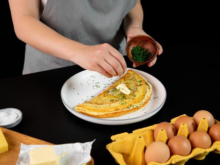 Uncover, add remaining cheese, and check the bottom of the omelette. It should be golden brown and the top of the omelette should be barely set with the melted cheese. Slide the omelette onto a plate, folding in half as you go. Garnish with chives and serve with a piece of toast and a salad. Enjoy!