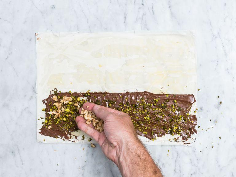 Pre-heat oven to 180°C/350°F. Brush 3 sheets of phyllo dough with melted butter and lay one upon the other. Coat an 8 – 10- cm/3 – 4-in. wide stripe of the dough with Nutella, leaving room on all the edges. Top with a third of the chopped pistachios and walnuts.