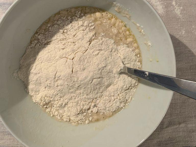 Start adding flour to the bowl little by little while mixing with a big spoon. 