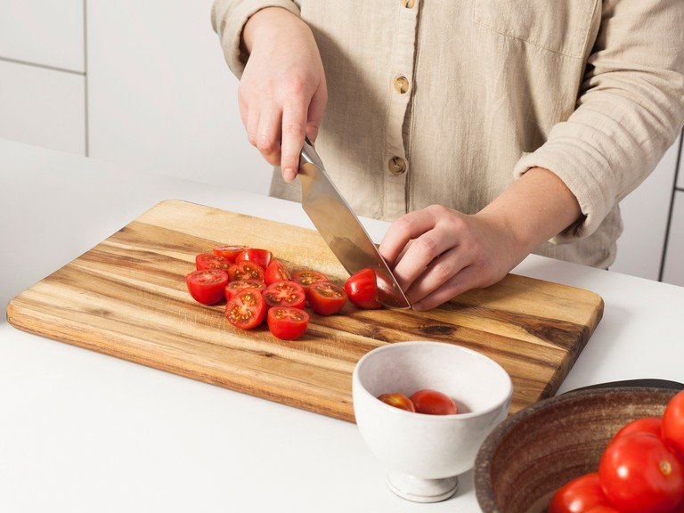 Die Tomaten vierteln und die Kerne entfernen. Die Kirschtomaten halbieren. Einen großen Topf mit Wasser zum kochen bringen.
