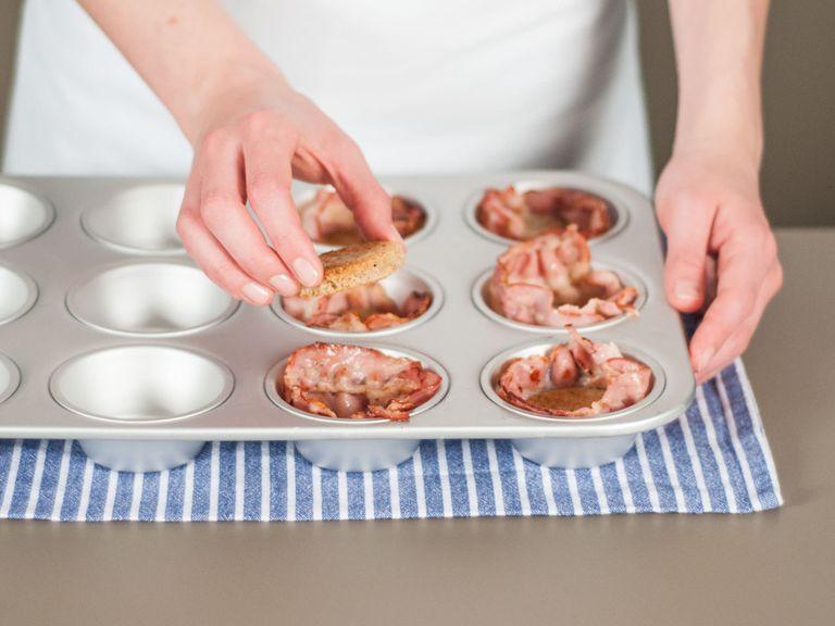 Place two strips of bacon in each muffin cup. Then, place bread on top of bacon and press gently so that it fits securely in the muffin cup.
