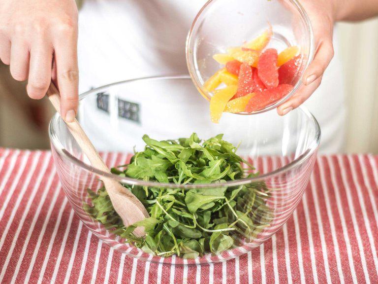 Carefully fold the citrus fillets into the arugula, then mix with the dressing. Once the salad is plated, top with avocado and season with salt and pepper. Serve with a few dollops of pesto.
