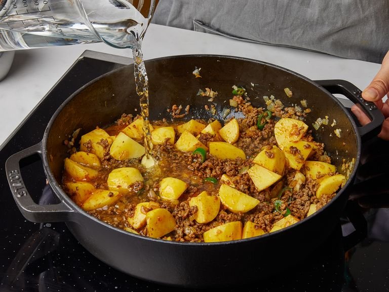 Add the green chili, turmeric, garam masala, and fry for approx. 1 min. Add tomato paste and fry 2 min. more. Add the potatoes, stir to incorporate, then deglaze the pan with water. Bring to a boil, then reduce to a steady simmer, cover, and cook for approx 20 min.