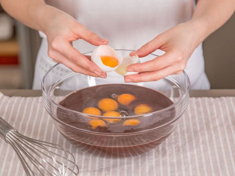 Eier und eine kleine Prise Salz zu der Schokoladenmasse hinzugeben und mit einem Schneebesen gut verrühren.