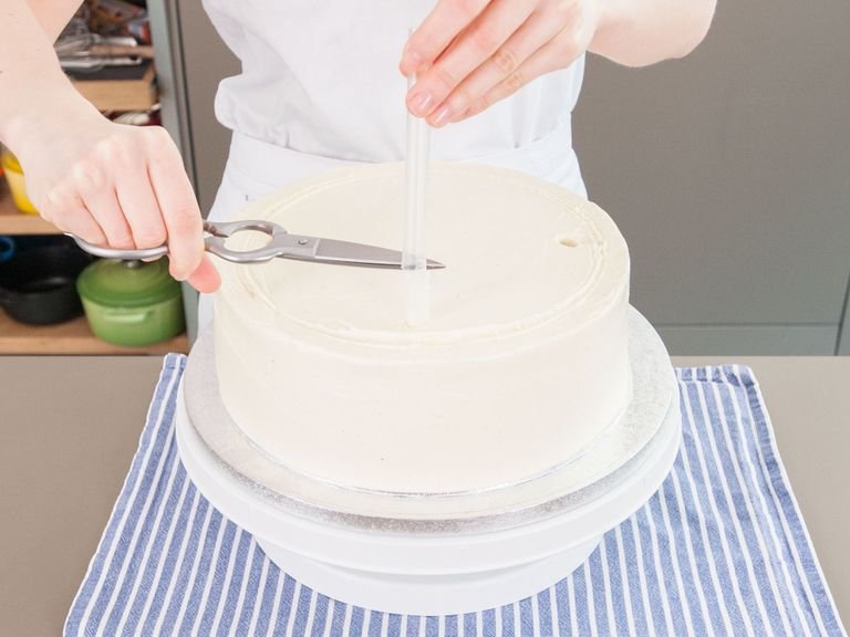 Just inside the marks on the 10-inch/25-cm tier, insert straws (or wooden dowels) at 12-, 3-, 6-, and 9-o’clock positions. Mark where cake meets straw, then remove it and trim just below the mark so that it disappears when reinserted in cake. Push straws back into cake. Repeat process with 8-inch/20-cm tier, using 3 straws at 12-, 4-, and 8-o’clock positions. Use buttercream to smooth over holes.